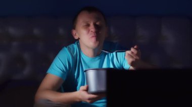 Adam geceleri televizyon izliyor dondurma yiyor ve gülümsüyor, yakın plan, kamera hareketi.
