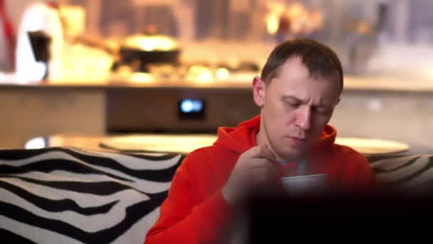 晚上，一个孤独的男人坐在沙发上，吃着冰激凌，看电视. — 图库视频影像