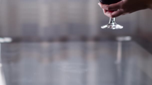 Изящная женская рука кладет бокал вина на стол, светлый фон — стоковое видео