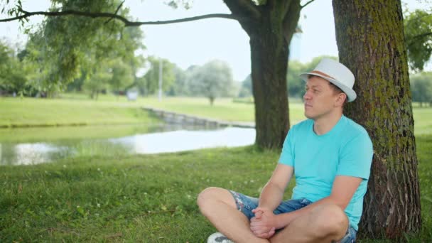 Jeune Homme Repose Alors Est Assis Sous Arbre Dans Parc — Video