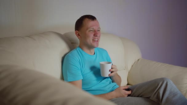 Osamělý Mladý Muž Hrnkem Čaje Sedí Večer Pohovce Dívá Televizi — Stock video