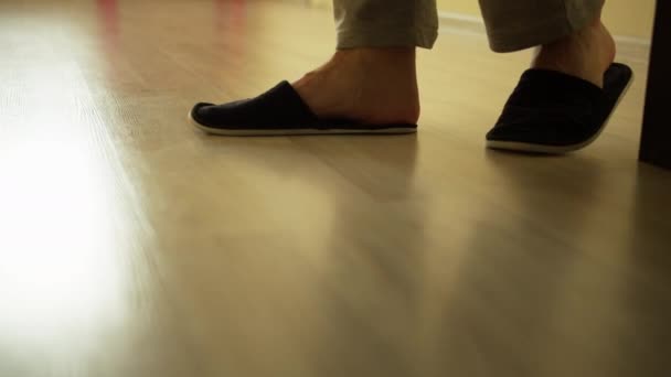 A man in slippers walks on a light floor, camera tracking — Stock Footage Man Slippers Walks Light Floor Camera Tracking Stock Video