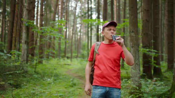 年轻的男性游客背着背包 站在黑暗的森林里 一边喝着瓶子里的水 一边跟踪着摄像机 — 图库视频影像