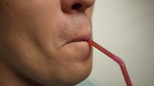 Närbild av en man läppar dricka en drink genom en plast cocktail tube — Stockvideo