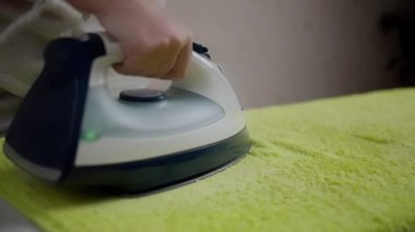 Kadın ev hanımı yumuşak havluyu ütülüyor, rafa odaklanıyor, yakın plan.