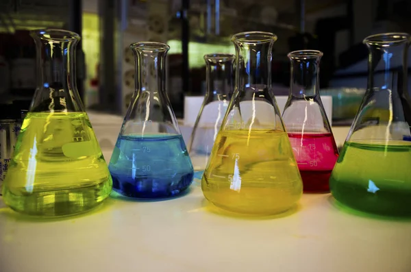 Composição de solução colorida de frasco cônico forrado em um banco — Fotografia de Stock