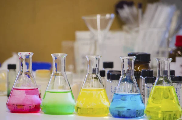 Multiple colorful solution in conical flask lined on a bench in