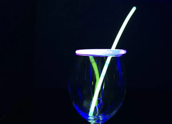 Blue and green glow stick on a wine glass with light painting ag