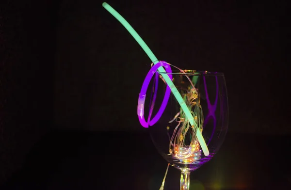 Blue and green glow stick on a wine glass with colorful light re