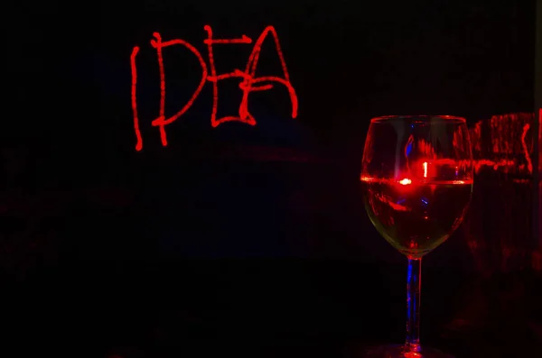 Laser drawn idea writing in a black background with wine glass r