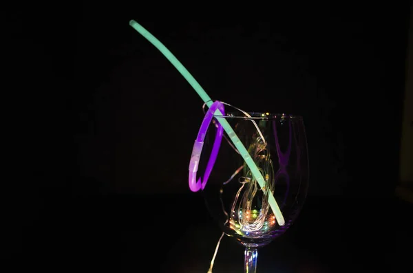 Blue and green glow stick on a wine glass with colorful light re