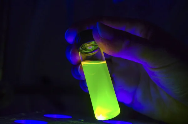 Investigador mano sosteniendo la reacción fotoquímica verde en vidrio vi — Foto de Stock