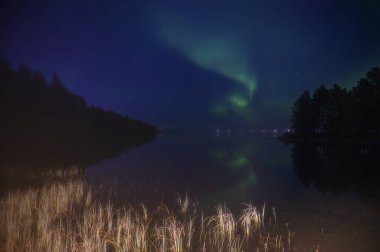 Bulutlu yıldızlı koyu mavi altında Kuzey ışık Aurora borealis