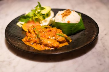 Endonezya 'nın Bali kentindeki turistik bir gezide siyah bir tabakta servis edilen kremalı tavuk ve salatayla süslenmiş akşam yemeği.