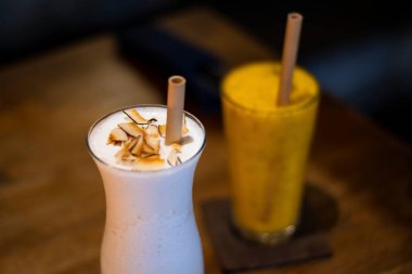 Çevre dostu restoran için bir bardak milkshake ve ahşap pipetli mango smoothie.