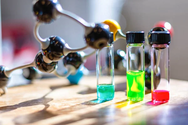 Multicolour solutions in different vials under the light with molecule model in a chemistry laboratory for healthcare research