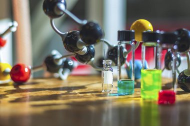 Işığın altında farklı cam şişelerde kimyasal bileşik çözeltileri ve sağlık araştırmaları için bir kimya laboratuvarında molekül modeli. 