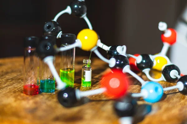 Chemical colourful solutions in different glass vials under the light with molecule model in a chemistry laboratory for healthcare research
