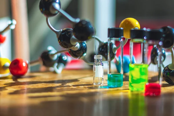 Chemical compound solutions in different glass vials under the light with molecule model in a chemistry laboratory for healthcare research