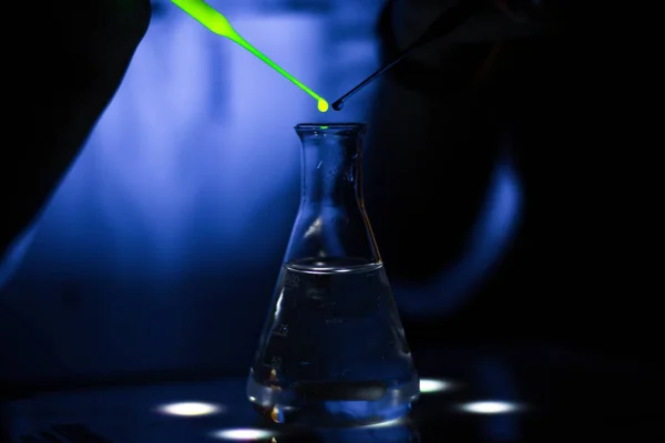 一位欧洲研究人员在黑暗化学实验室中研究一种绿色荧光化合物 用于药物开发 — 图库照片
