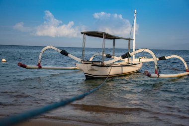 Endonezya 'nın Bali kentindeki turistik ziyaret sırasında beyaz bir silindir tekne mavi bir rok boyunca bağlanıyor.