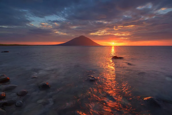 Volcano on the sea in the rays of the setting sun, sea of Okhotsk, Iturup island