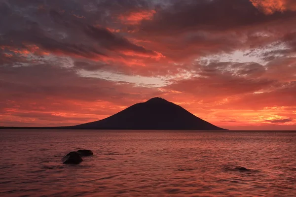 Volcano on the sea in the rays of the setting sun, sea of Okhotsk, Iturup island