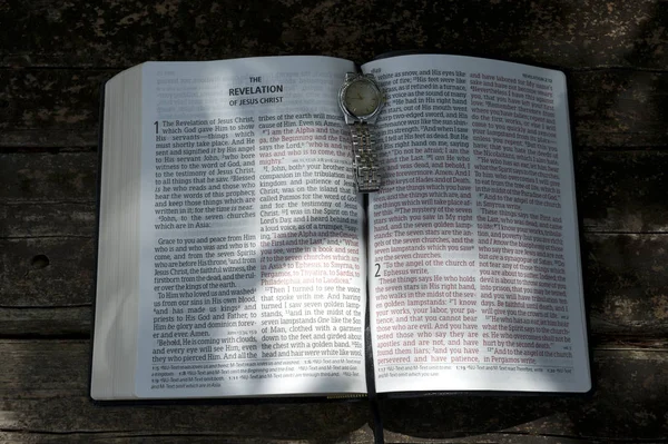 Horloge sur la Bible ouverte dans la Révélation de Jésus-Christ dans les chapitres 1 — Photo