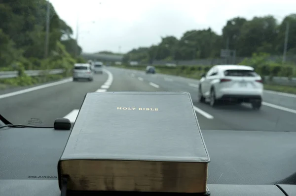 Sainte Bible dans la voiture. Voie rapide arrière-plan flou avec des voitures . — Photo