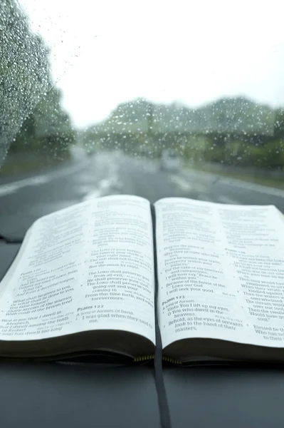 Belle vue sur la Sainte Bible ouverte dans le Psaume 121 le jour de tempête et de fortes pluies. Fond flou avec autoroute et voitures . — Photo