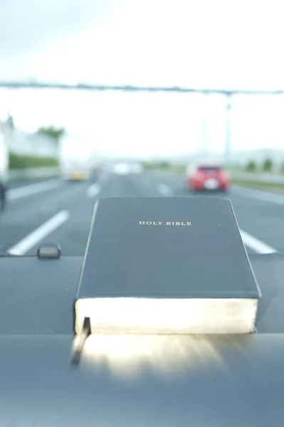 Bible fermée avec une lueur dorée. Fond flou autoroute avec des voitures. Espace de copie . — Photo