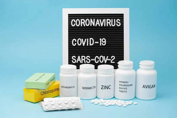 Klorokin, hidrokloroksin sülfat, çinko, Ivermectin ve Avigan. Şu anda COVID-19 tedavisinde kullanılan ilaçlardan bazıları. Kabarcık torbası ve dağınık haplar. Arkaplanda yazı tahtası. 