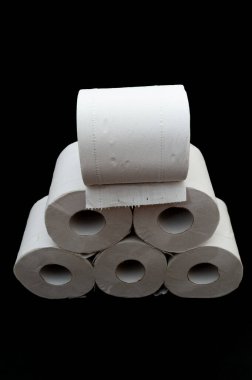 Tuvalet kağıdı ruloları istiflenmiş. Siyah arka planda izole edilmiş. Dikey çekim. Yakın plan. Ön görünüm. 