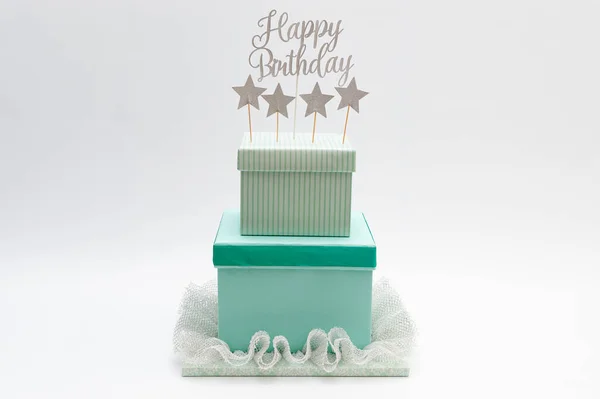 Fake cake - DIY Gift Box Cake. Birthday cake made with boxes. Decorated with colored paper, pleated lace, star shapes and the phrase: Happy Birthday. Isolated on white background. Copy space.