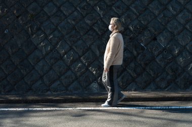 Coronavirus (COVID-19) ve diğer bulaşıcı hastalıklara karşı koruma amaçlı gözlük ve beyaz maske takan 40-49 yaş arası bir kadın. Uzayı kopyala Yatay çekim.