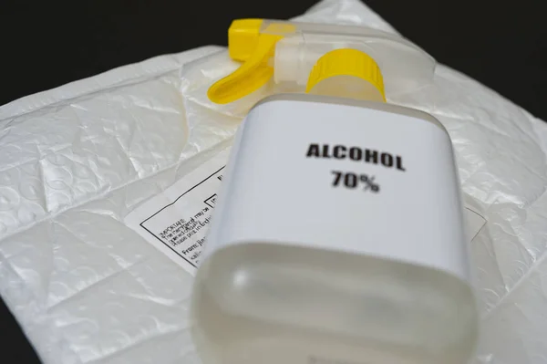 % 70 alkol spreyi baloncuk ambalajlı zarfın üstünde Post etiketi var. Siyah arka planda izole edilmiş. Seçici odak.
