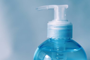 Pompa şişesinin başını yakın plan çek. Alkol jeli ya da el dezenfektanı. Coronavirus 'a karşı koruma (COVID-19). Mavi arka planda izole edilmiş. Boşluğu kopyala.