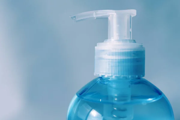 Pompa şişesinin başını yakın plan çek. Alkol jeli ya da el dezenfektanı. Coronavirus 'a karşı koruma (COVID-19). Mavi arka planda izole edilmiş. Boşluğu kopyala.