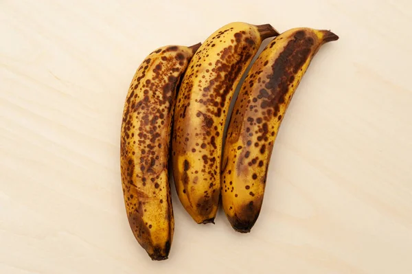 Trzy Dojrzałe Banany Wyizolowane Jasnym Drewnianym Tle Widok Góry Przestrzeń — Zdjęcie stockowe