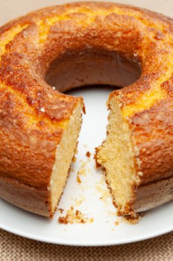 Mısır unu keki (Bolo de Fuba) Brezilya stilini beyaz bir tabakta kesti. Jüt 'te izole edilmiş. Ön manzara. Yakın plan. Dikey çekim.