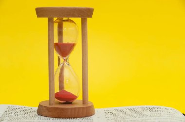 Peygamber Ezekiel 'in kitabında İncil' in açık olan 7. ayetinin üstüne kırmızı kum saati. Sarı arka planda izole edilmiş. Yakın plan. Yatay çekim.