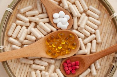 Vitaminler, mineraller ve ahşap kaşıklardaki besin takviyeleri örülmüş bambu bir tabağın içinde. Üst Manzara. Yakın plan. Kavram: Sağlıklı yaşam tarzı.