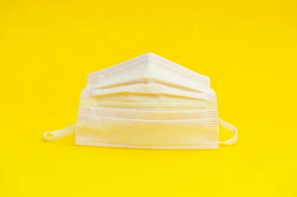 Health care - Pink surgical mask for protection against Coronavirus (COVID-19) and other contagious diseases. Isolated on yellow background. Close-up. Horizontal shot.