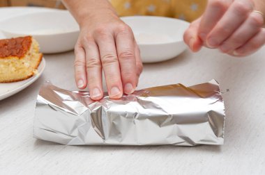 Portekizce BOLO GELADO olarak bilinen geleneksel Brezilya tatlısı- adım adım: Kadın dilimlenmiş keki alüminyum folyoya sarıyordu. Yakın plan..