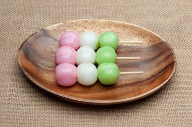 Dango Mochi adındaki geleneksel Japon tatlısı ahşap tepside yeşil çayla servis ediliyor. Jüt arka planda izole edilmiş. Yakın plan. Üst Manzara. Yatay çekim.