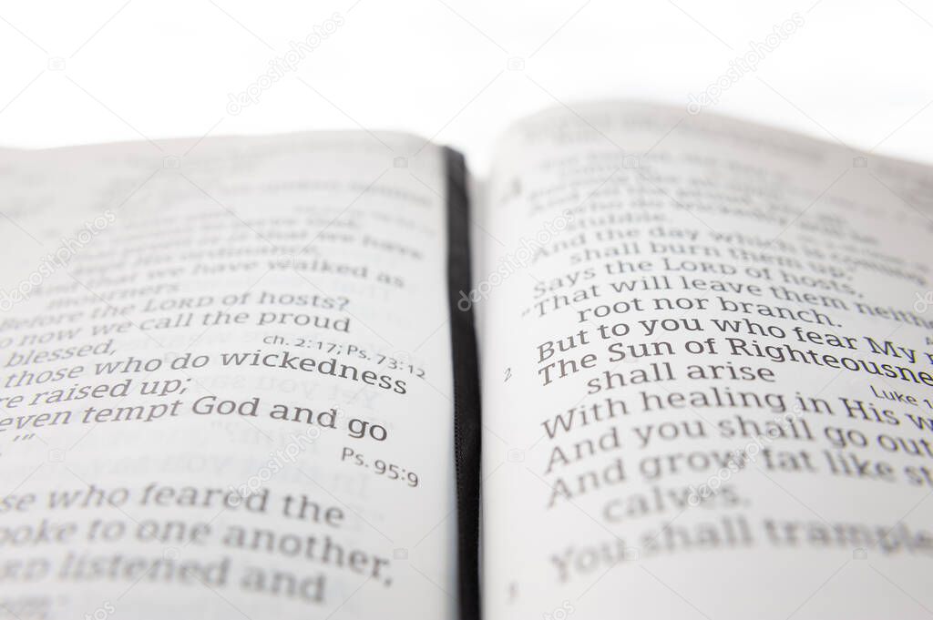 Open holy bible highlighted in Malachi 4:2. Isolated on white background. Selective focus.