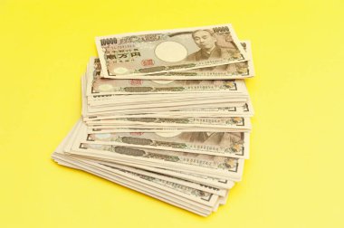 10 bin yen (10 bin yen) banknotlar istiflendi. Japon parası. Kağıt para. Sarı arka planda izole edilmiş. Üst Manzara. Boşluğu kopyala.