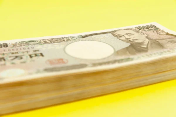 蓄積された1万円の銀行券 日本のお金 紙幣だ 黄色の背景に隔離された サイドビュー — ストック写真