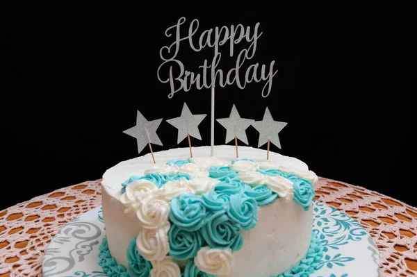 生日蛋糕上涂着白色和蓝色的糖霜 上面装饰着星星的形状和一句格言 生日快乐 被黑色背景隔离 前面的景色横向射击 — 图库照片