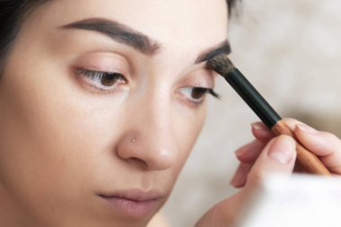 Kaş farı uygulaması, kaş modelleme makyajı, yakın çekim. Moda makyaj, güzellik konsepti ile kadın model yüz
